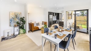 Un salon moderne comprenant un coin repas, une cuisine et une porte-fenêtre coulissante donnant sur un jardin.