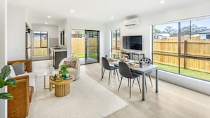 Un salon moderne avec un coin repas, de grandes fenêtres et une vue sur le jardin.