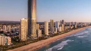 A coastal cityscape with a prominent tall building, a beachfront, and numerous surrounding high-rise buildings. - Cloudview Retreat | Luxe Skyhome Experience (Surfers Paradise)