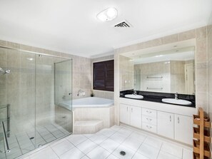 Ein modernes Badezimmer mit einer gläsernen Dusche, einer freistehenden Badewanne und einem Waschtisch mit zwei Becken.