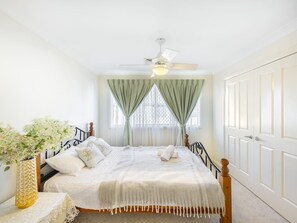 A bedroom with a bed, curtains, a ceiling fan, and a door. - Private Cinema! 5Beds Spacious Villa Near Shops (Calamvale)
