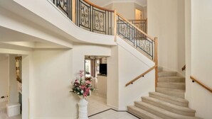 A spacious interior with a curved staircase, white walls, and a tiled floor. - Private Cinema! 5Beds Spacious Villa Near Shops (Calamvale)