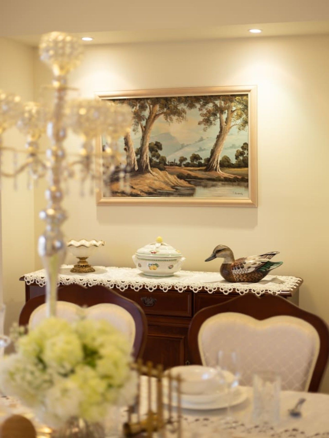 Zona pranzo con tavolo apparecchiato per due, un quadro appeso e un decoro a forma di uccello sul tavolo.