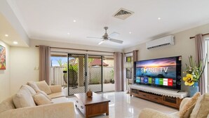 A spacious living room with a large flat-screen TV, two sofas, a coffee table, and a ceiling fan. - Private Cinema! 5Beds Spacious Villa Near Shops (Calamvale)