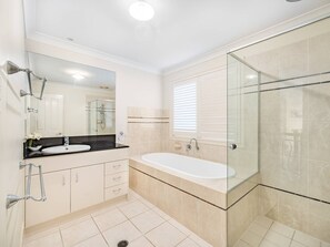A bathroom with a glass-enclosed shower, a white bathtub, and a sink with a black countertop. - Private Cinema! 5Beds Spacious Villa Near Shops (Calamvale)