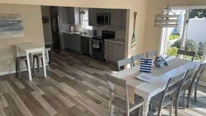 A modern kitchen with dark cabinets, a central island, and a dining area with a white table and chairs. - Bogus Point. A lakeside retreat. (Hilton)