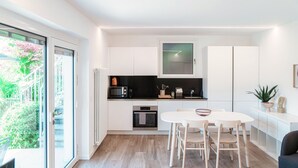 A modern kitchen with white cabinets, a black countertop, and a dining area with a round table and chairs. - Studio apartment with lakeview terrace (LA PALMA 3) (Collina d'Oro)