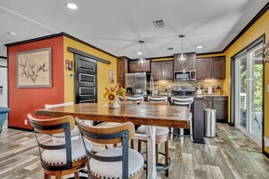 Una cocina moderna con una isla central, electrodomésticos de acero inoxidable y un comedor con sillas de madera.