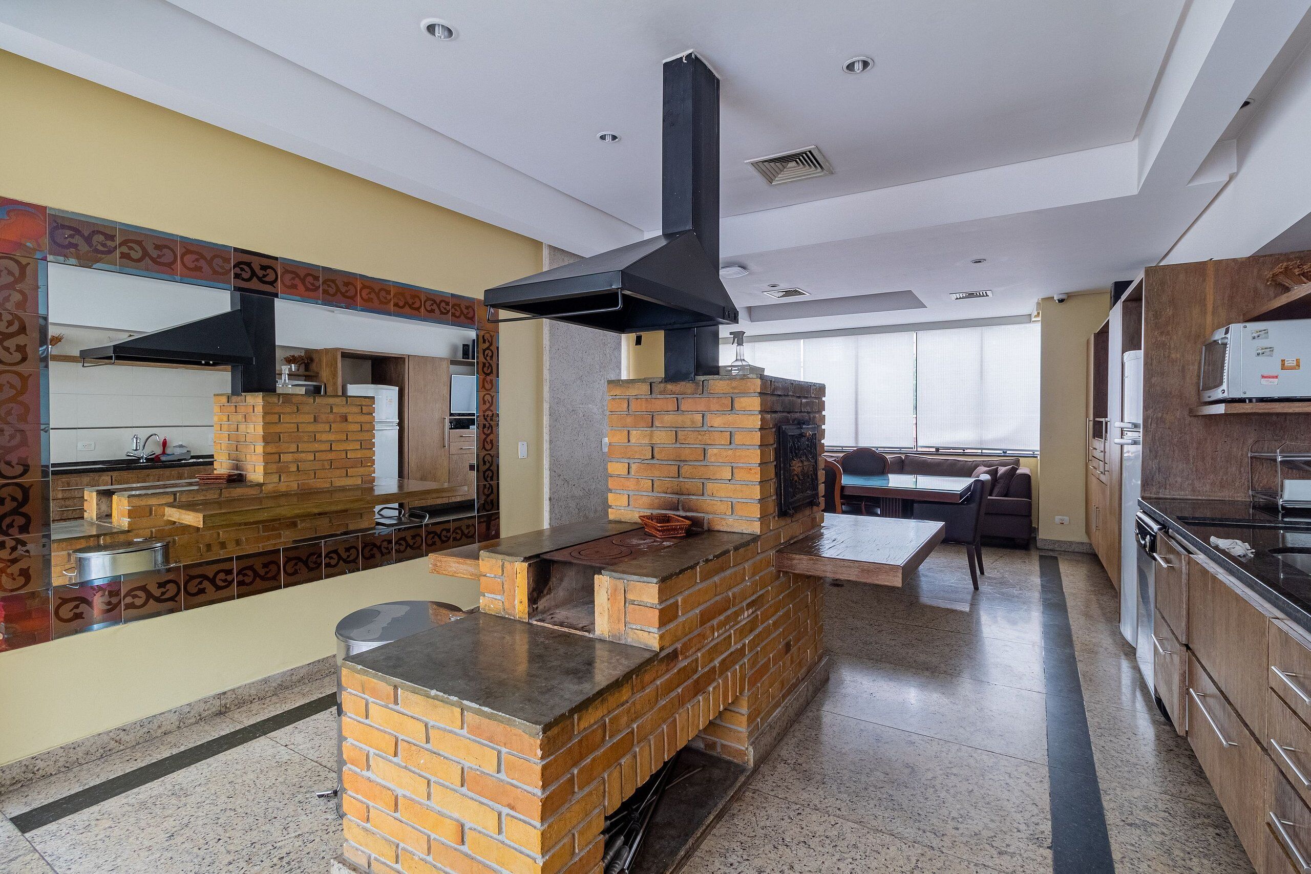 A kitchen with a brick oven, a large mirror, and a dining area with a table and chairs.