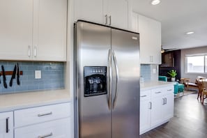 Una cocina moderna con electrodomésticos de acero inoxidable, armarios blancos y un dispensador de agua integrado.
