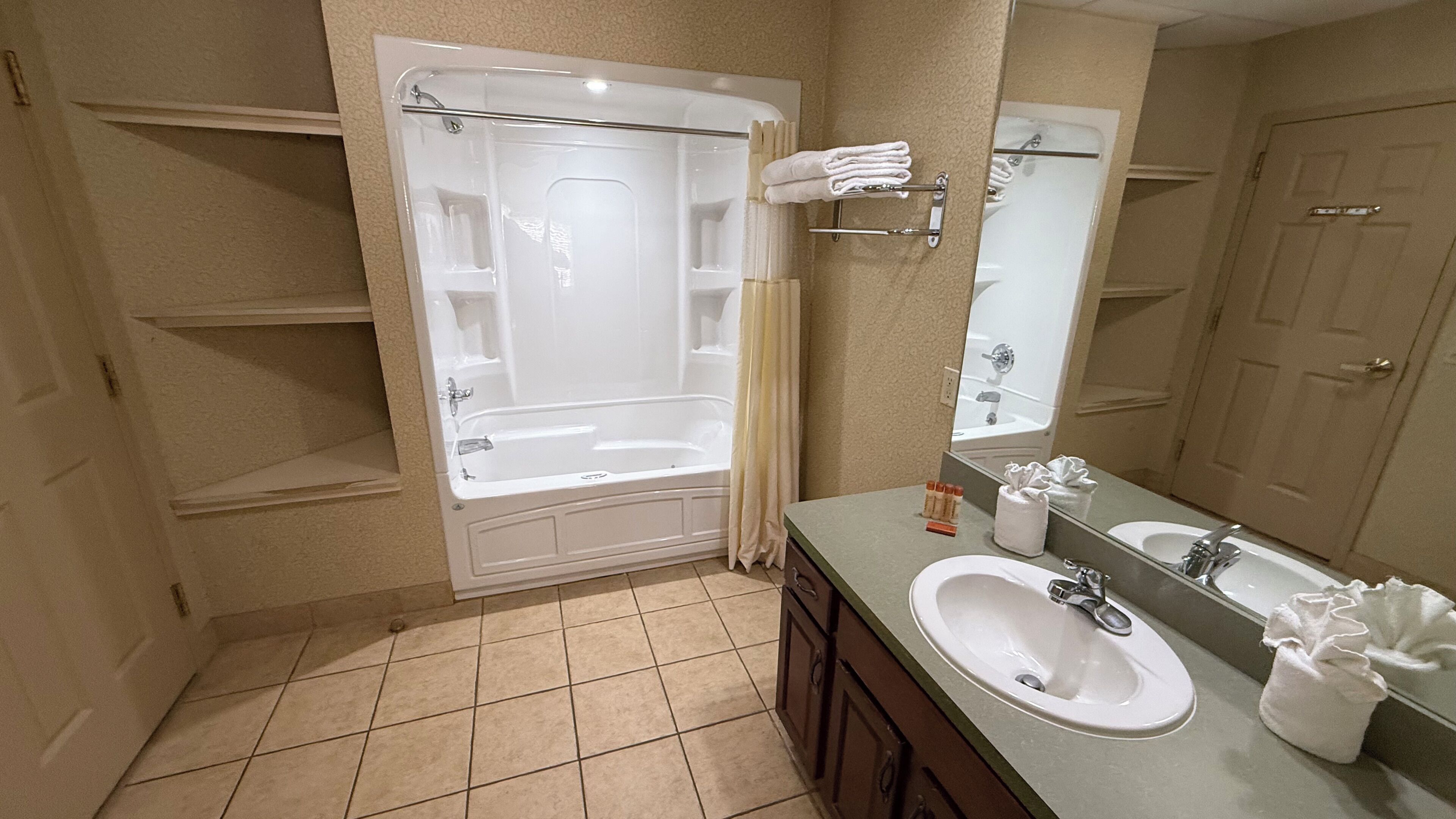 A bathroom with a bathtub, a sink, a mirror, and a shower curtain.