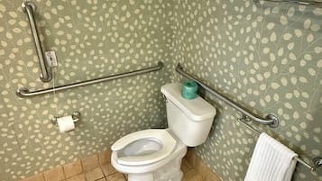 A bathroom with a toilet, grab bars, a towel rack, and a patterned wall.