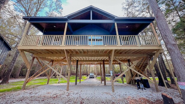 Une cabane en bois dotée d’un balcon, entourée d’arbres.
