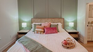 Une chambre à coucher comprenant un lit, des tables de chevet, un ventilateur de plafond et une petite table de nuit avec une lampe.
