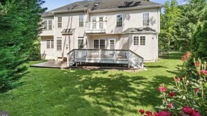 Ein zweigeschossiges Haus mit einer Veranda und einer überdachten Terrasse.