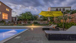 A pool area with lounge chairs and a yellow umbrella, surrounded by a stone wall and greenery. - Nice apartment in Stara Vas with WiFi (Stara Vas)