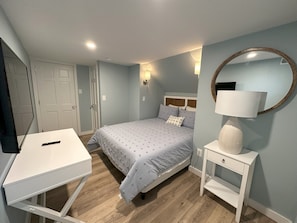 A bedroom with a bed, bedside table, lamp, and a desk with a remote control. - BEACH BLOCK GEM! 5BR 2 Full BA 1stFloor! Late Aug & Sept weeks still available (Ocean City)
