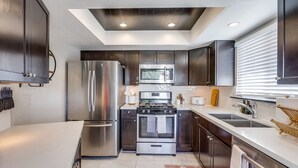 Une cuisine moderne dotée d’appareils électroménagers en acier inoxydable, de meubles de couleur sombre et d’un puits de lumière.
