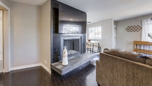 Un salon moderne avec une cheminée, un parquet foncé et un espace détente.