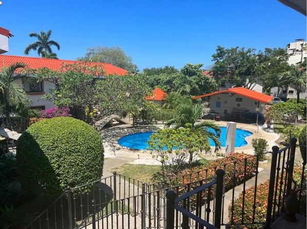 A pool area with a circular hot tub, surrounded by greenery and palm trees.