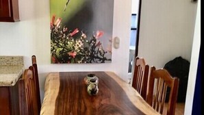 Un coin repas avec une table et des chaises en bois, un tableau représentant un oiseau accroché au mur et un petit objet décoratif posé sur la table.