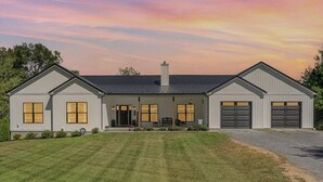 Une maison à deux étages avec un porche à l’avant, un garage et une pelouse bien entretenue.