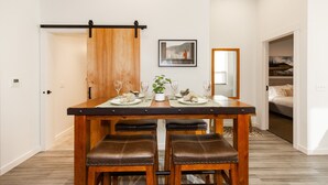 A dining area with a wooden table and four leather chairs, a sliding barn door, and a framed picture on the wall.
