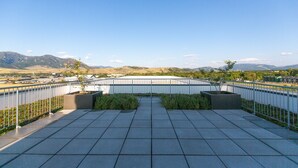 A rooftop terrace with a view of mountains and a parking lot. - The Cat's Meow:Midtown Bozeman (Bozeman)