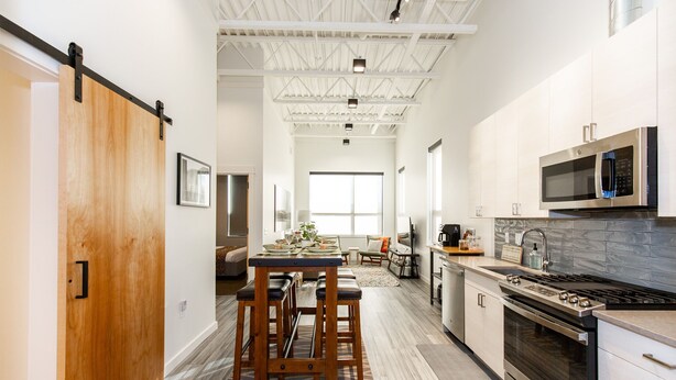 A modern kitchen with a central island, stainless steel appliances, and a sliding barn door.