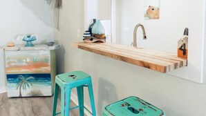 A bathroom with a wooden vanity, a sink, and a mirror. There is a small stool and a decorative item on the vanity.