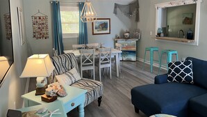 A cozy living room with a dining area, a blue sofa, and a kitchen area with a mirror and decorative items.