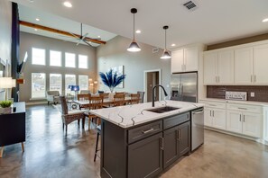 A modern kitchen with a central island, white cabinets, and a stainless steel refrigerator.
