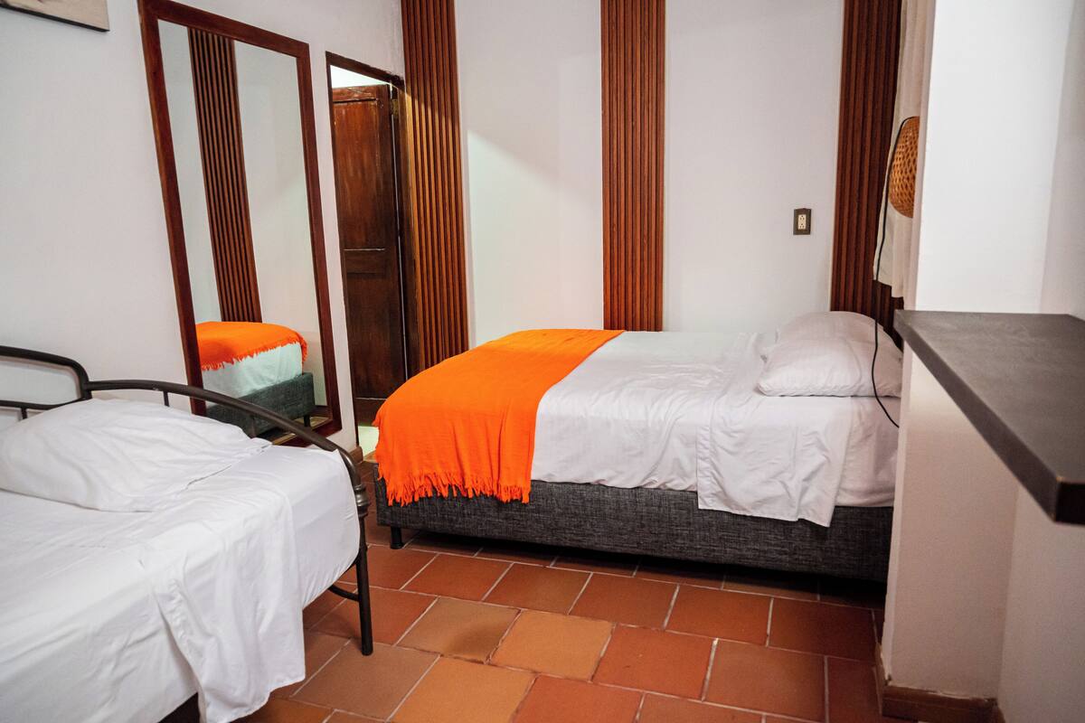 A bedroom with two beds, a wooden wardrobe, and a desk.