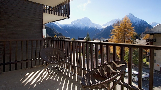 A balcony with two chairs and a view of snow-capped mountains.