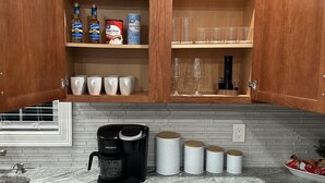 Una cocina con armarios de madera, una cafetera y recipientes de almacenamiento.