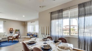 Un comedor con una mesa dispuesta para cuatro, una araña y vistas a un balcón.
