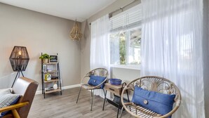 Una habitación con dos sillas de mimbre, una estantería y una lámpara colgante.