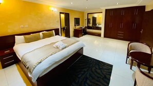 Une chambre d’hôtel avec un grand lit, un bureau, une chaise et une armoire.