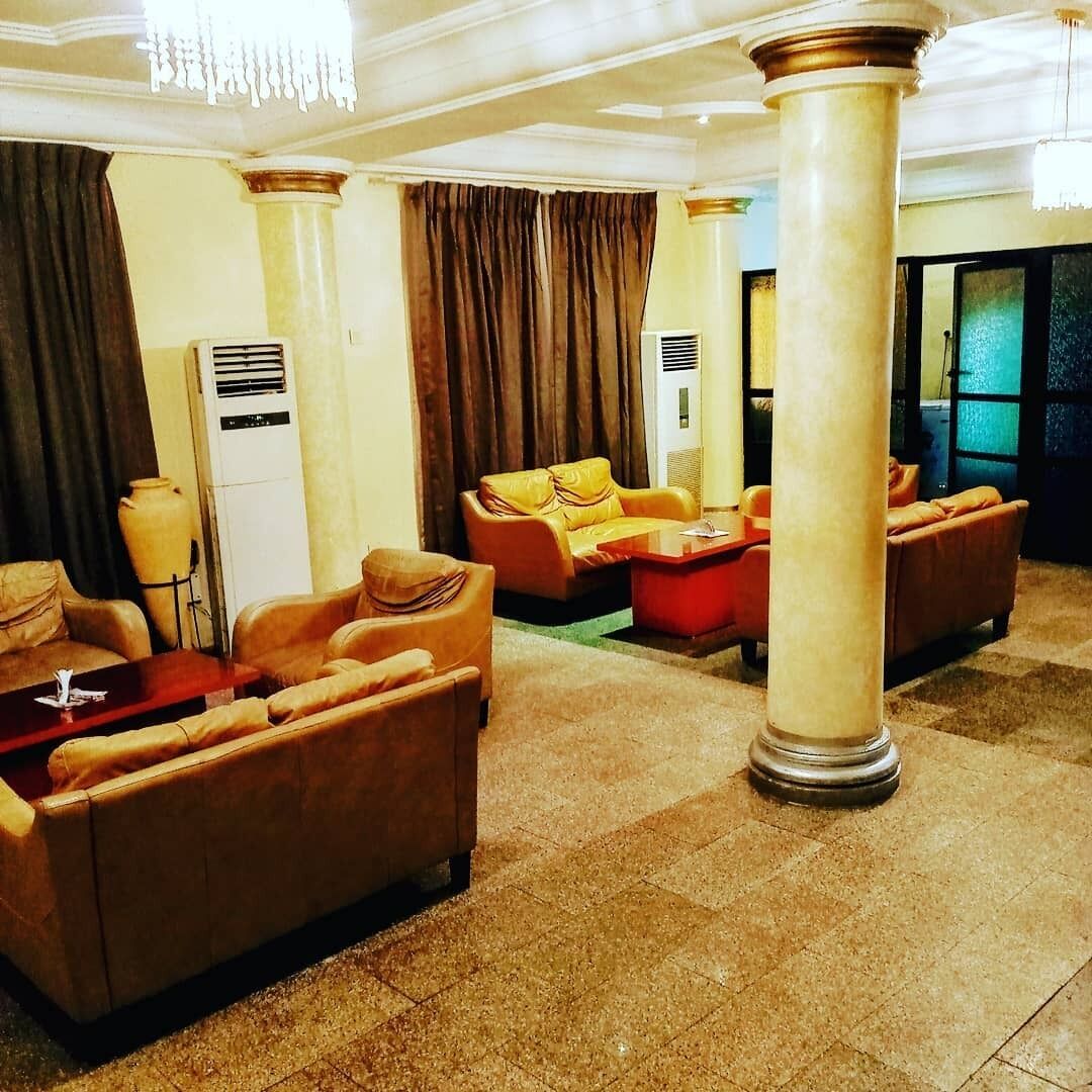 A lobby with leather sofas, a red coffee table, and a large pillar.