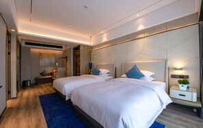Una habitación de hotel moderna con dos camas, un espejo grande y una mesita de noche con una planta.