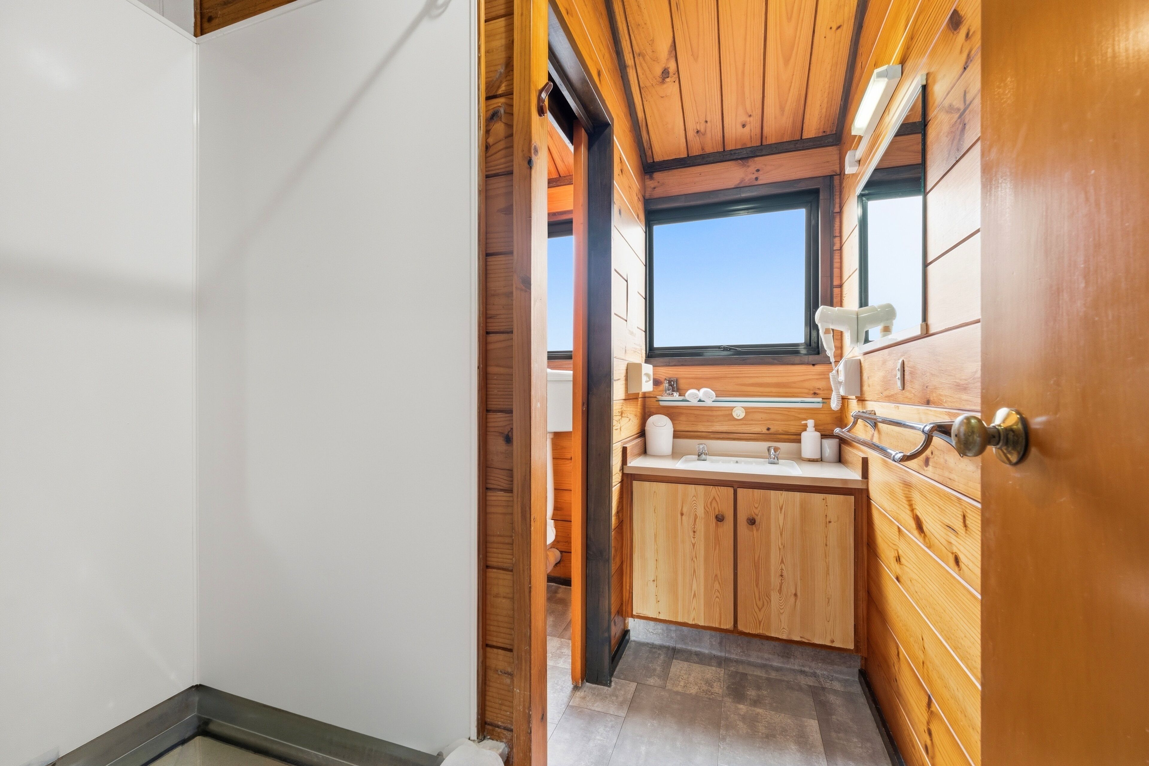 Interior de madera con ventana, un lavabo y armarios.
