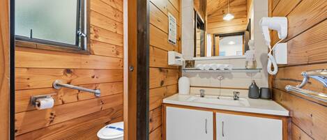 A wooden-paneled bathroom with a toilet, sink, and hand dryer.