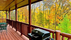 A covered outdoor deck with a grill, wooden railing, and a view of autumn foliage. - Timber Ridge Lodge -HOT TUB- POOL (Harpers Ferry)
