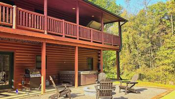 Een chalet met een overdekte veranda, buiten zitplaatsen en een barbecuehoek.