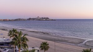 Une plage offrant une vue sur une ville côtière, avec notamment un bâtiment imposant situé sur une colline.