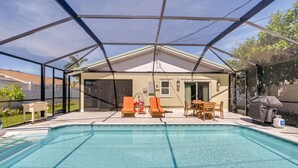 A covered outdoor swimming pool with lounge chairs and a table, surrounded by a house and a fence. - Updated Naples Retreat w/ Private Pool & Patio! (Naples)