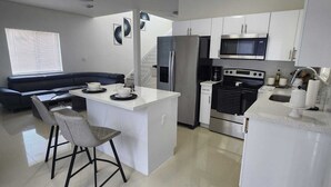 A modern kitchen with white cabinetry, a central island with bar stools, a built-in oven, and a microwave. - We are located in the heart of Miami, 10 min away from Downtown, Beaches, M.I.A (Miami)