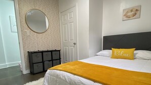 A bedroom with a bed, a mirror, a door, and a wall with a geometric pattern.