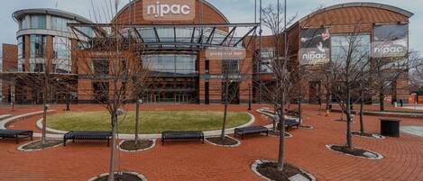 Un edificio de njpac con un patio central, bancos y árboles.