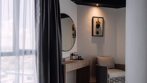 A modern hotel room with a wooden desk, a chair, a large mirror, and a framed picture on the wall. - Impiana by Roxy Hotel  (Kuching)